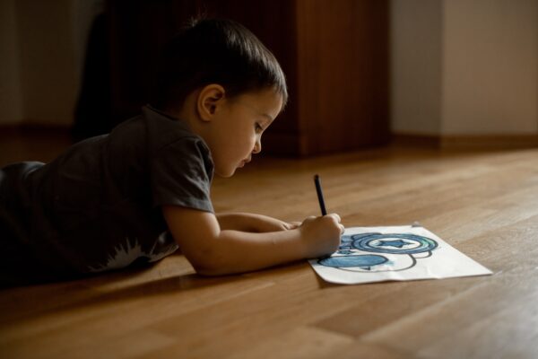 A little boy draws a drawing with colored pencils