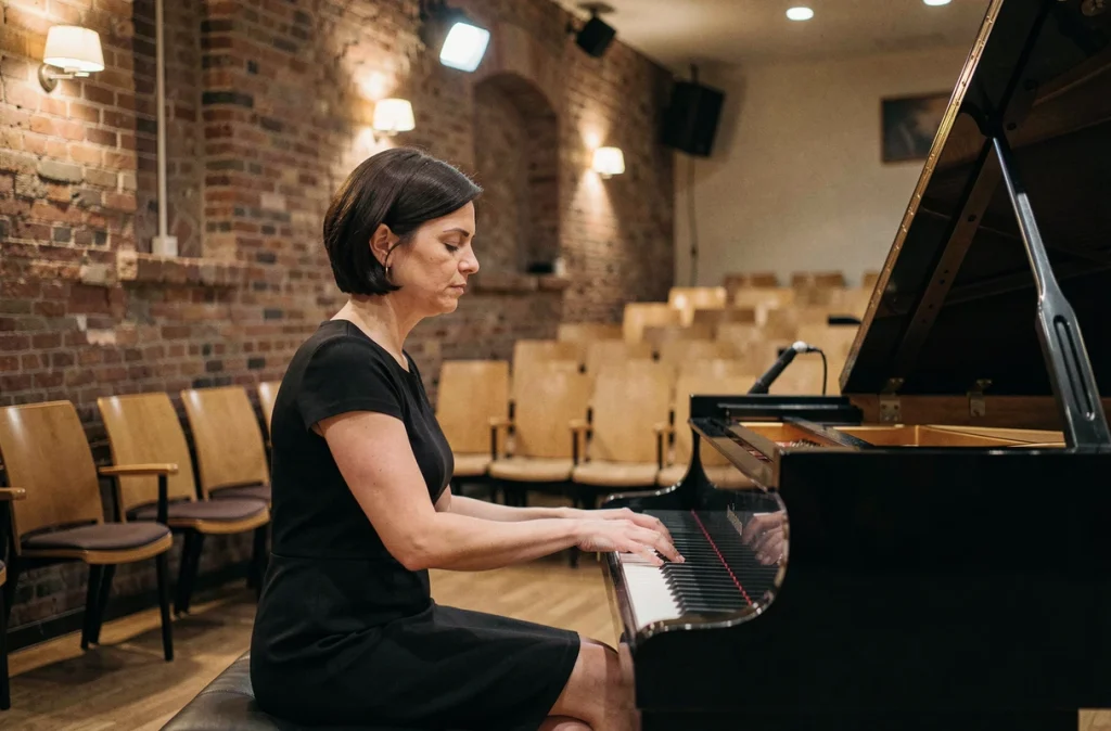 Femme chanteuse seule sur scène au piano dans une petite salle de concert intimiste, expression de concentration et de solitude artistique