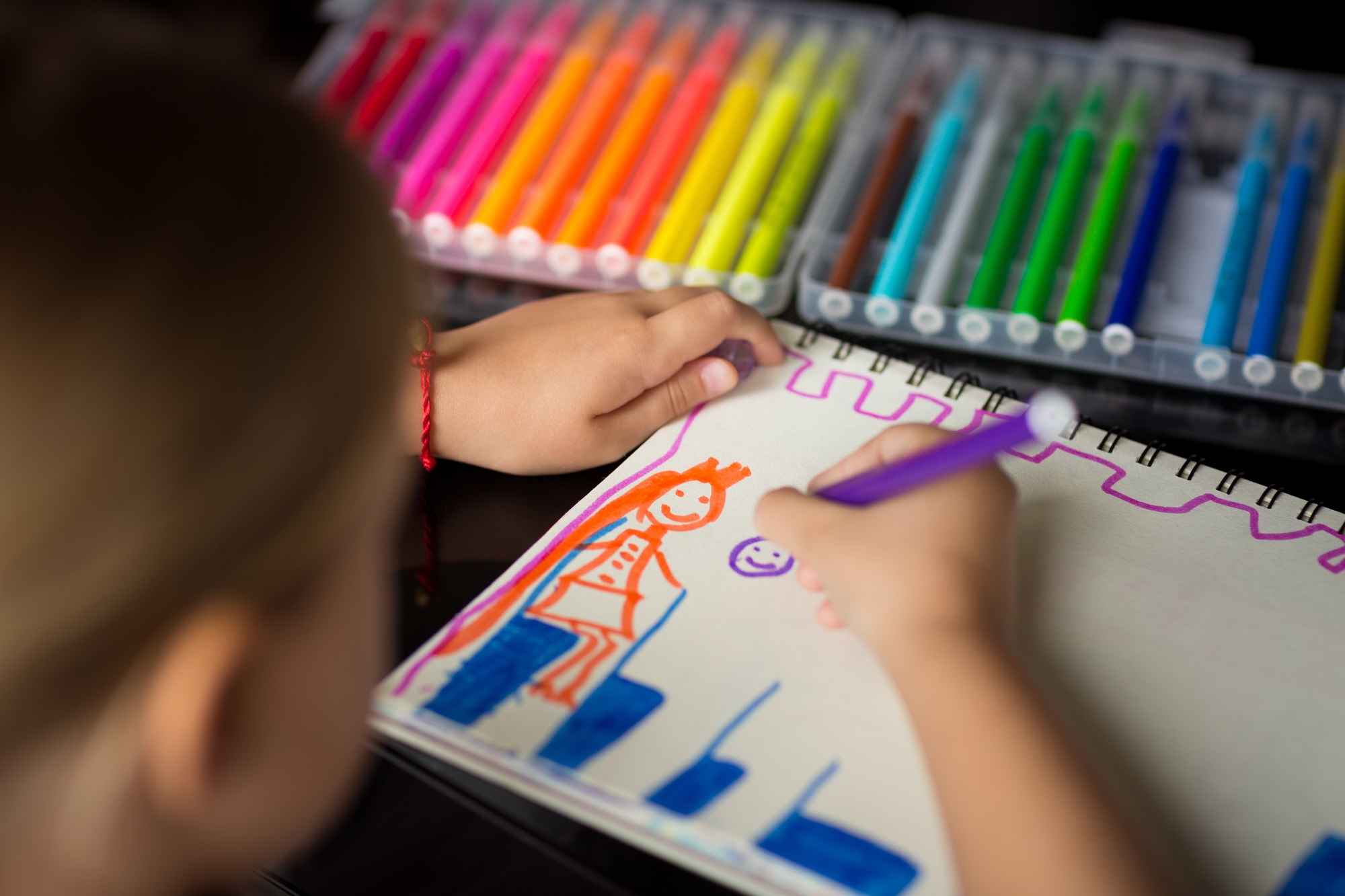 Child painting princess with colored pencils on paper blank