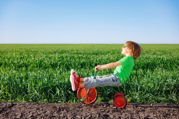 Happy child riding bike outdoor in spring green field