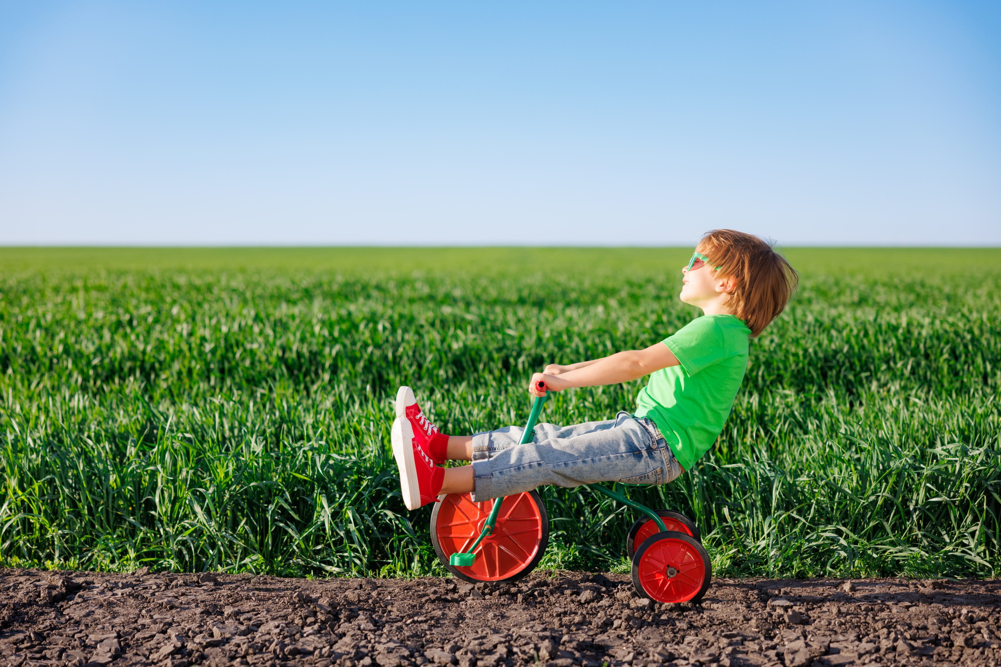 Happy child riding bike outdoor in spring green field