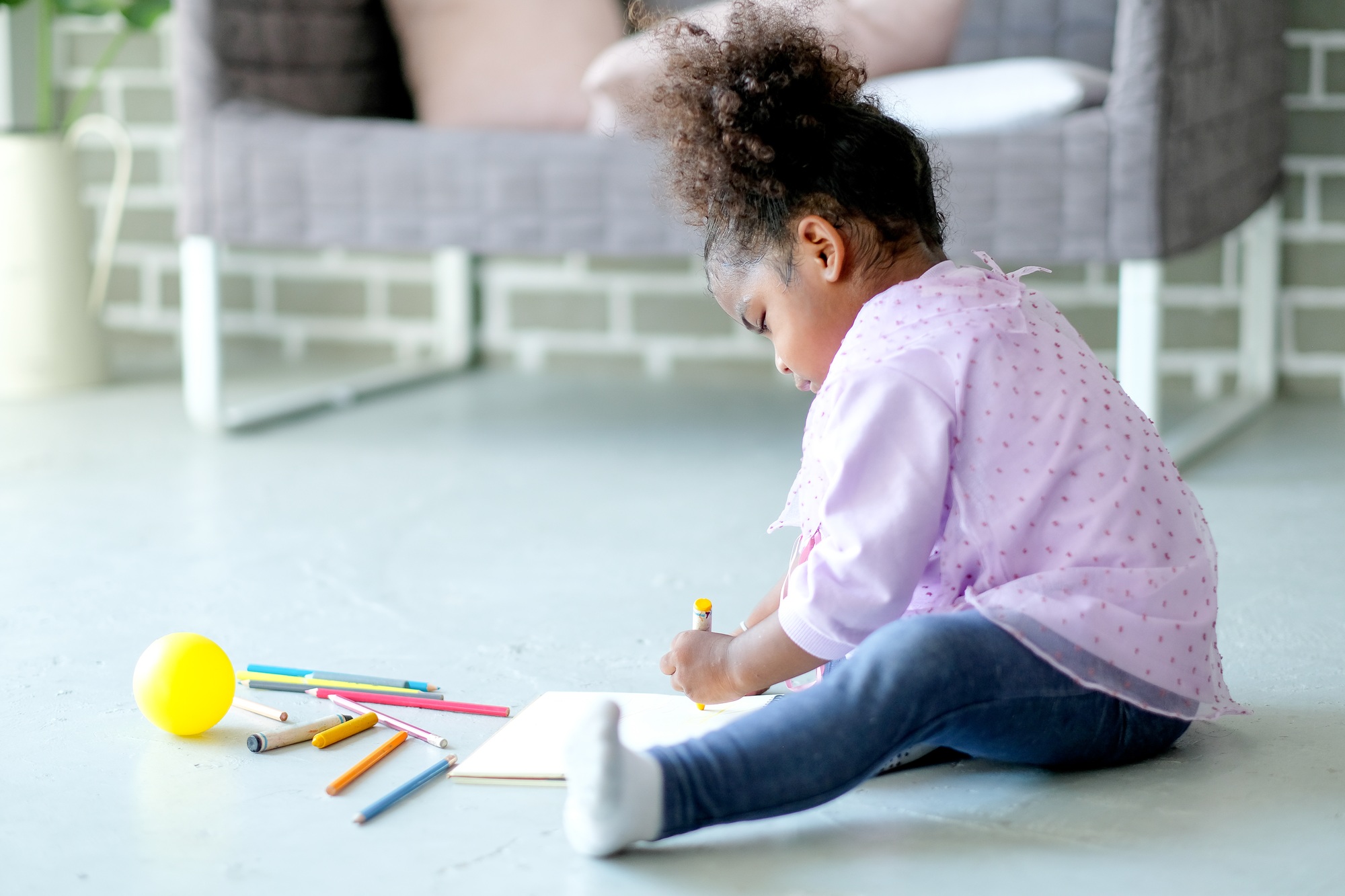 Little African American enjoy with writing or drawing by colored pencils on notebook