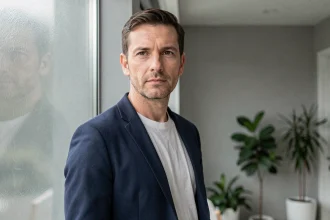 Portrait d'un homme discret en veste marine près d'une fenêtre, illustrant la protection de la vie privée face à la notoriété