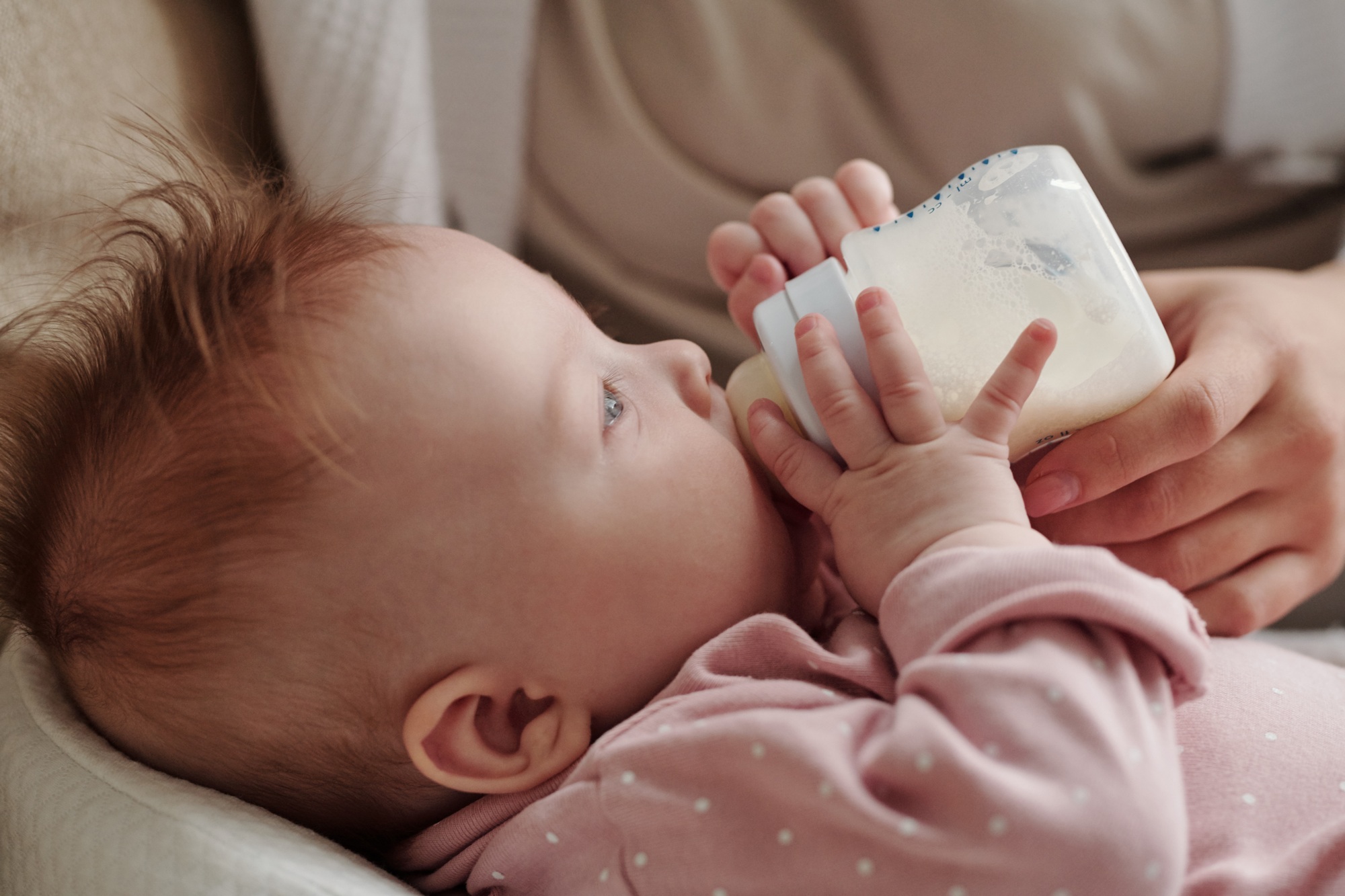 Side view of adorable baby girl eating milk